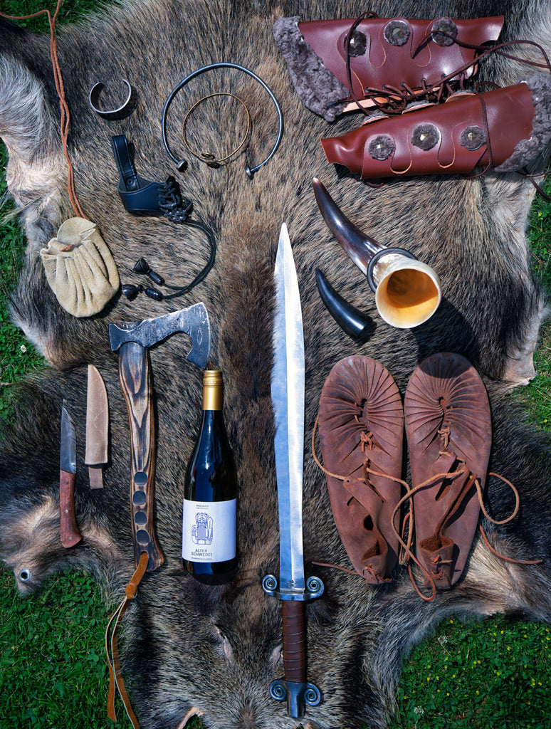 Weißwein Halvard - Alter Schwede von Weingut Schwedhelm Flasche mit Wikinger Ausrüstung auf einem Wildschwein Fell