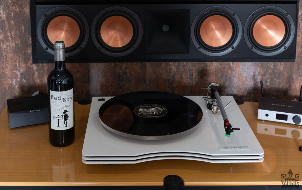 Audiophiler Lifestyle mit Bad Boy Bordeaux von Jean Luc Thunevin, Plattenspieler und Lautsprecher.