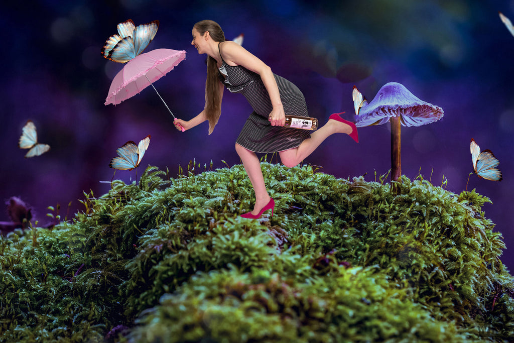 Bad Girl Rosé von Thunevin Fantasylandschaft mit Frau mit Weinflasche und rosa Schirm in der Hand auf Moos mit großem Pilz und Schmetterlingen