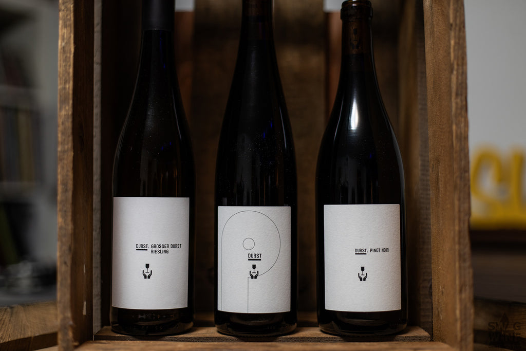 Drei Flaschen Wein von Andreas Durst - Pfalz stehen in einer Holzkiste bei Swagwine