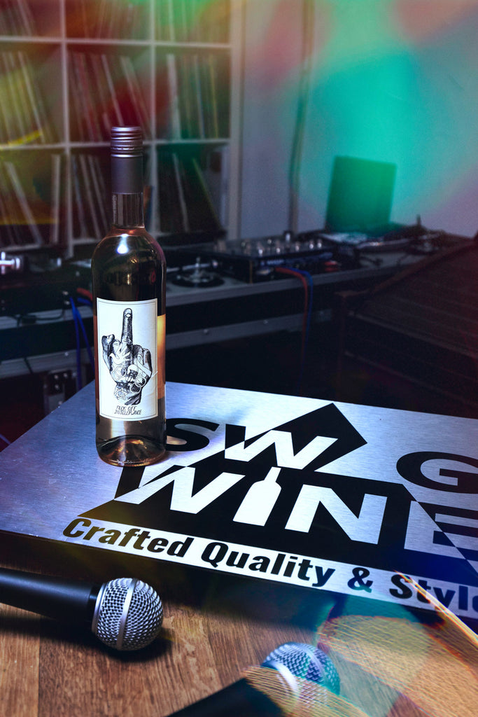 Fuck off intolerance Rosé Wein Flasche auf Swagwineschild mit Mikrofonen vor DJ Pult im Party Look
