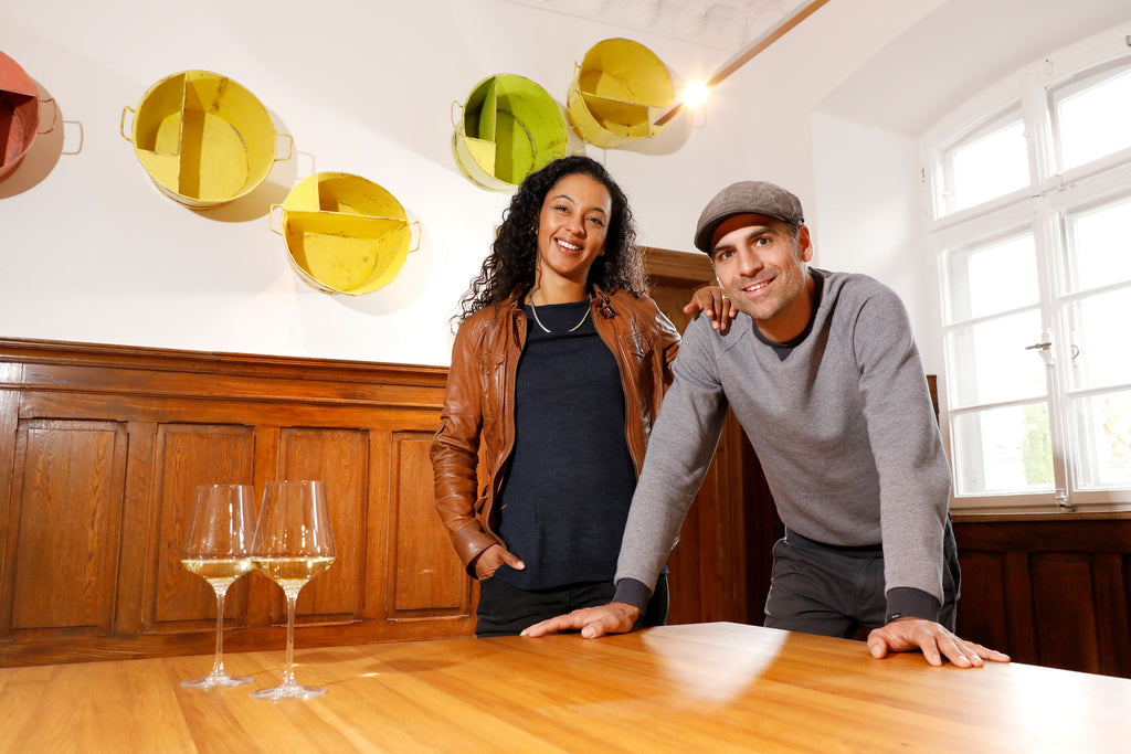 Weingut Spindler Forst Pfalz Markus und Lola stehen am Tisch im Weingut mit 2 Gläsern Wein 