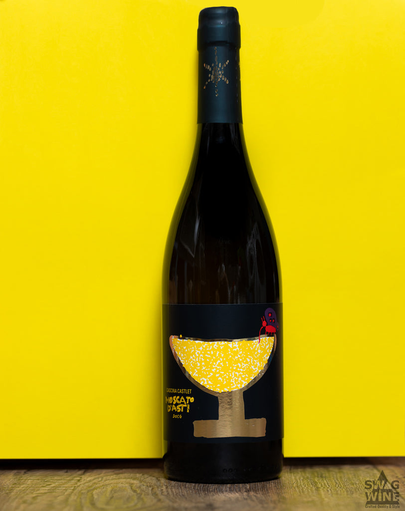 Moscato d'Asti von der Cascina Castlet im Piemont - Flasche mit gemaltem Schmetterling, der aus Sektschale trinkt vor gelbem Hintergrund auf Holzboden