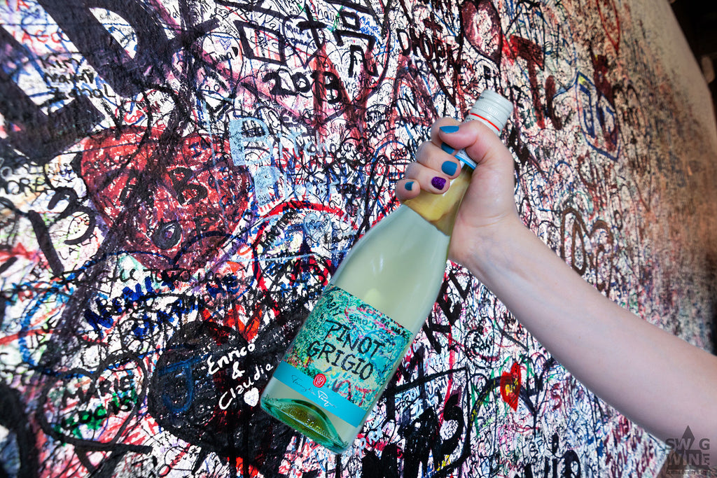 Pinot Grigio Weißwein von Pasqua Weinflasche in Frauenhand vor der Romeo und Julia Graffiti Wand in Verona