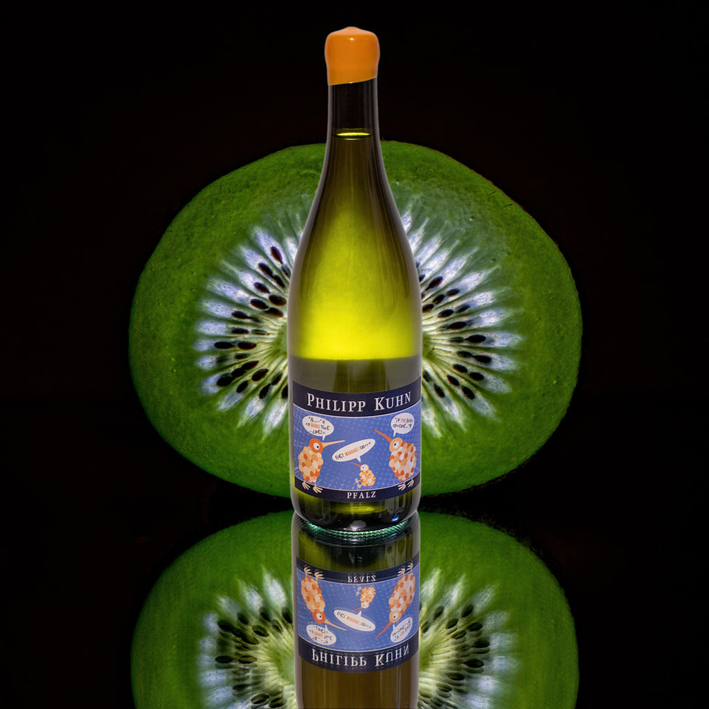 Piwi Waaaas Orange-Wein von Philipp Kuhn - Pfalz aus der Piwi Sorte Cabernet Blanc - Flasche vor einer Kiwi mit Spiegelung