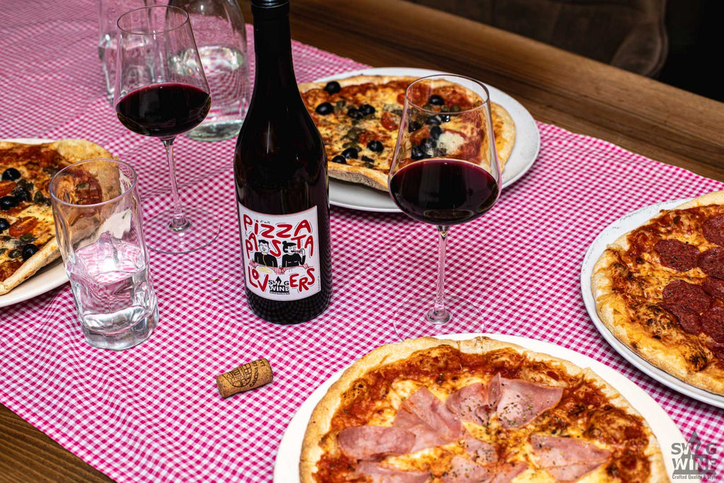 Swagwine For Pizza and Pasta Lovers - Italienischer Rotwein auf gedecktem Tisch mit Pizzatellern und eingeschenkten Gläsern