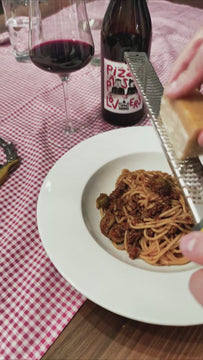 For Pizza & Pasta Lovers Rotwein - Parmesan über Spaghetti Bolognese reiben mit Weinflasche und Weinglas neben Teller
