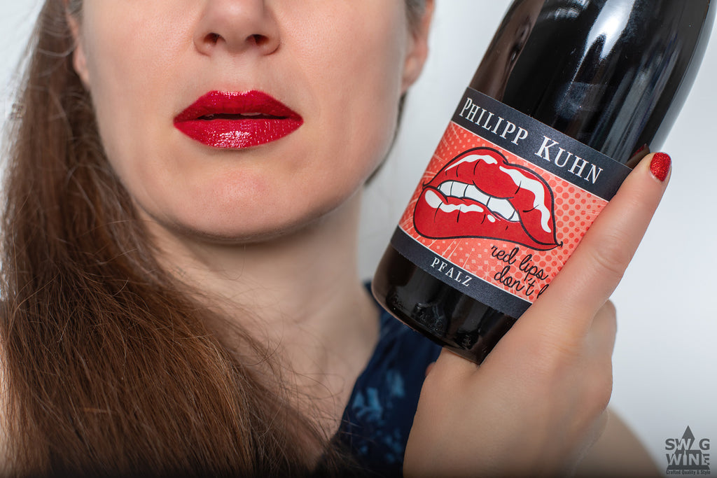Edle Rotwein Flasche Red Lips dont lie vom Weingut Philipp Kuhn - Pfalz in der Hand gehalten von einer Frau mit rot geschminkten Lippen