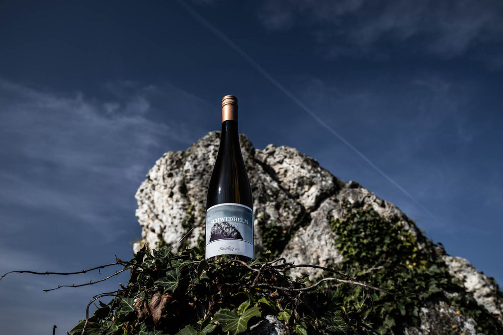 Riesling von Weingut Schwedhelm - Flasche vor Wotanfels unter blauem Himmel