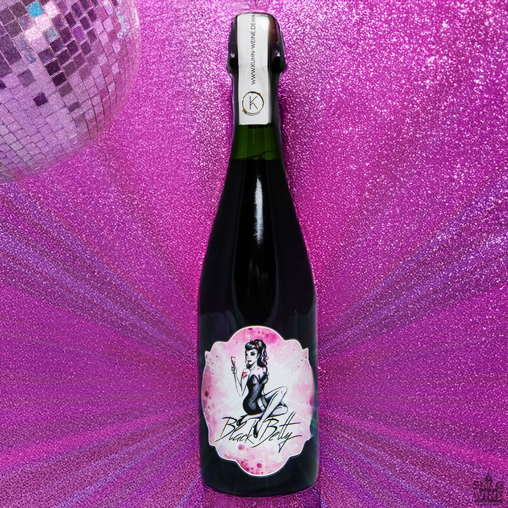 Roter Sekt Black Betty aus Syrah von Kuhn Weine aus Freiburg - Flasche mit Partylicht und Diskokugel vor pinker Glitzerwand