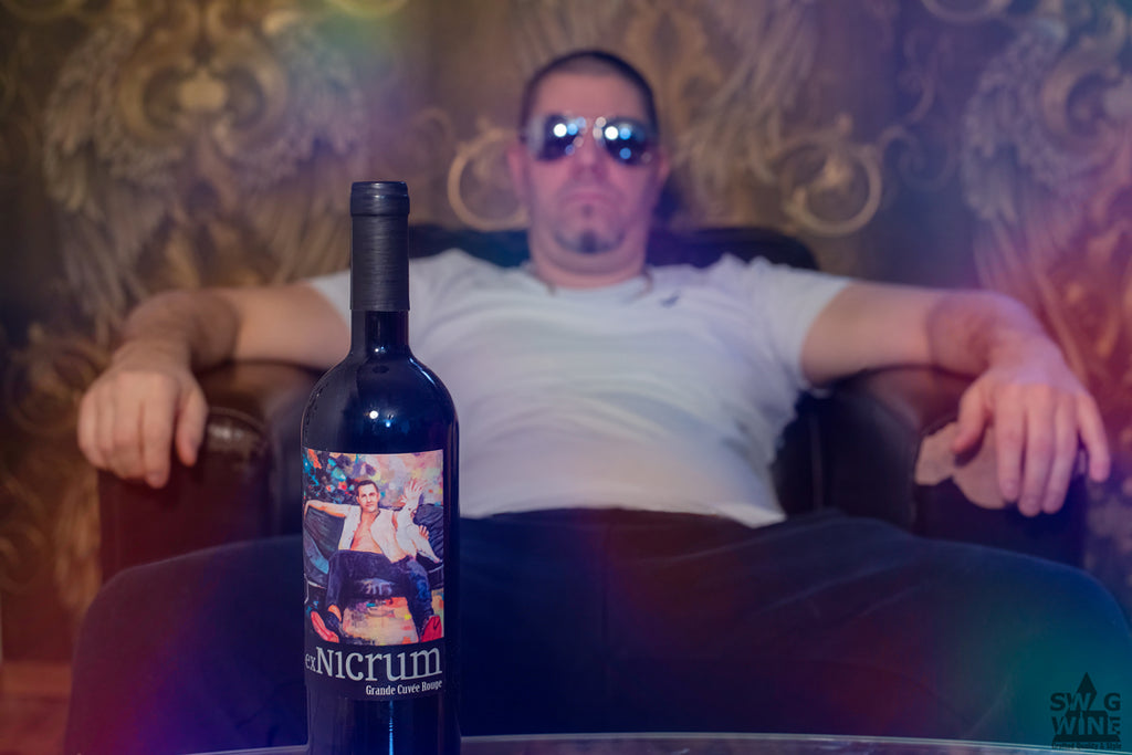 Rotwein Grande Cuvée Rouge von ex Nicrum Weinmanufaktur bei Swagwine - Flasche vor coolem Typ in Sessel mit Sonnenbrille und Partylicht