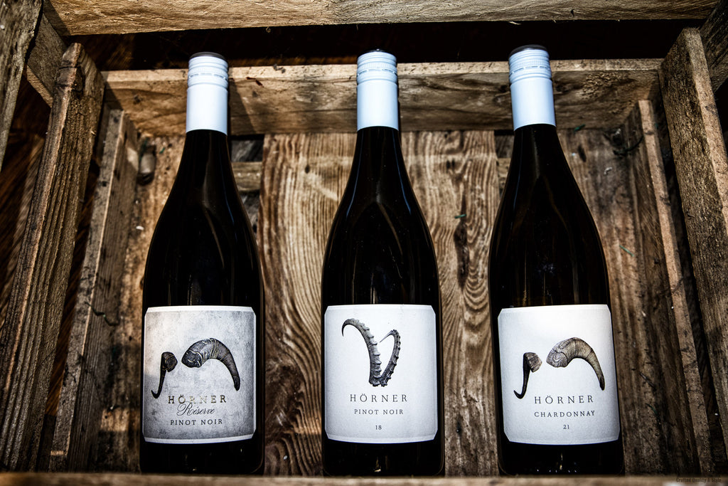 Drei Flaschen Wein von Weingut Hörner Südpfalz in einer Holzkiste. Steinbock und Widder