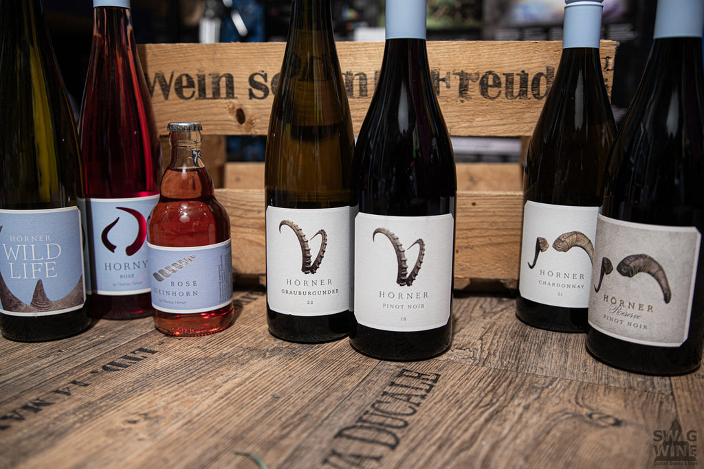 Weine von Weingut Hörner - Hainbachhof, Südpfalz der Linie Stier, Steinbock, Widder, Einhorn, Nashorn vor einer Holzkiste 