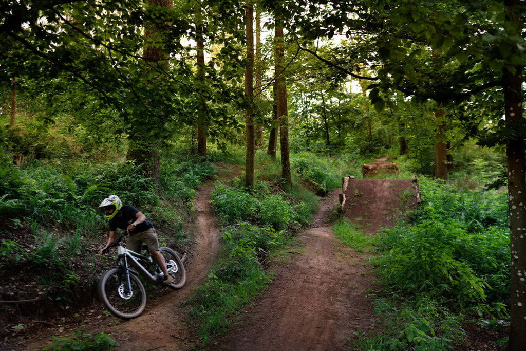 Winzer Christoph Golter auf dem Mountainbike im Wald - Foto vom Etikett des Weißburgunder Downhill