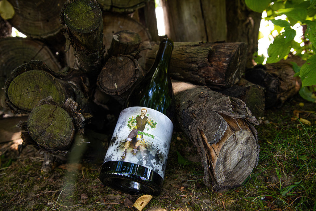 Weißburgunder Tripple B von Dschey Dschey Wines aus der Südpfalz - Weinflsache lehnt an Holzstapel