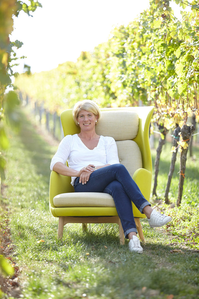Winzerin Tina Pfaffmann sitzt auf einem Sessel im Weinberg