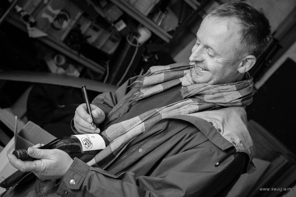 Winzer Andreas Durst signiert Weinflasche mit Sylvaner für Swagwine