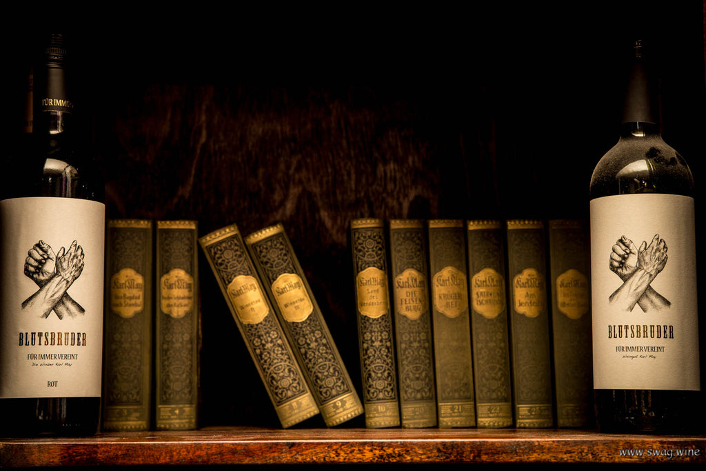 Blutsbruder Rotwein Cuvée von Karl May zwei Flaschen im Bücherregal mit Karl May Romanen
