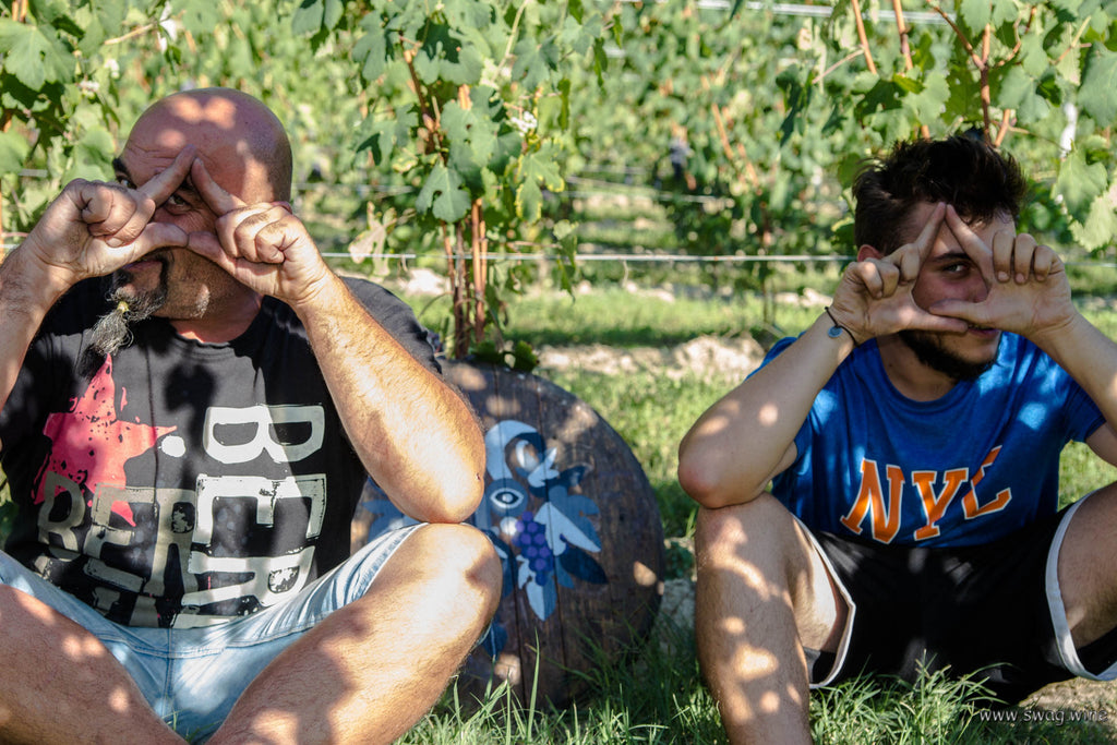 Carlo und Erik Revello im Weinberg zeigen das Swagwine Zeichen: Das Auge trinkt mit