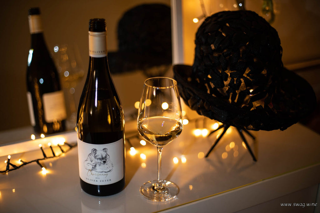 Chardonnay Haardt von Oliver Zeter aus der Pfalz - Flasche und eingeschenktes Glas im warmen Licht auf einem Schminktisch mit einem Hut