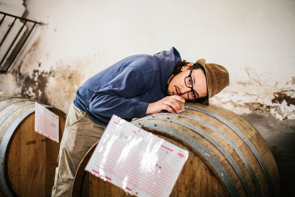 Winzer Lukas Krauß - Mann mit Hut - hört an einem Weinfass im Weinkeller