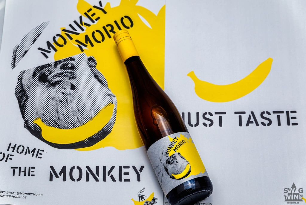 Monkey MorioWeißwein von Hanewald-Schwerdt aus der Pfalz - Flasche vor Plakat Home of the Monkey