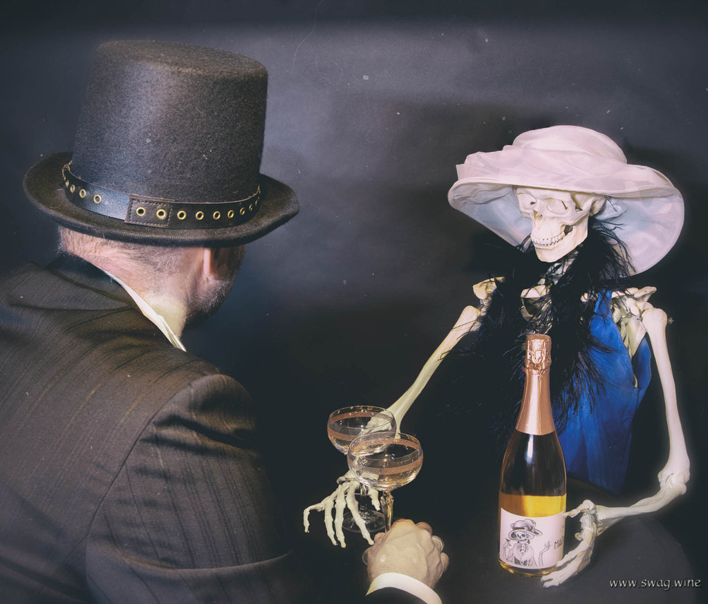 Rosé Sekt Madame von Wohlfahrt-Franke aus dem Rheingau - Skelett in 20er Jahre Frauenkleidung trinkt mit Herrn in Anzug und Zylinder aus Sektgläsern