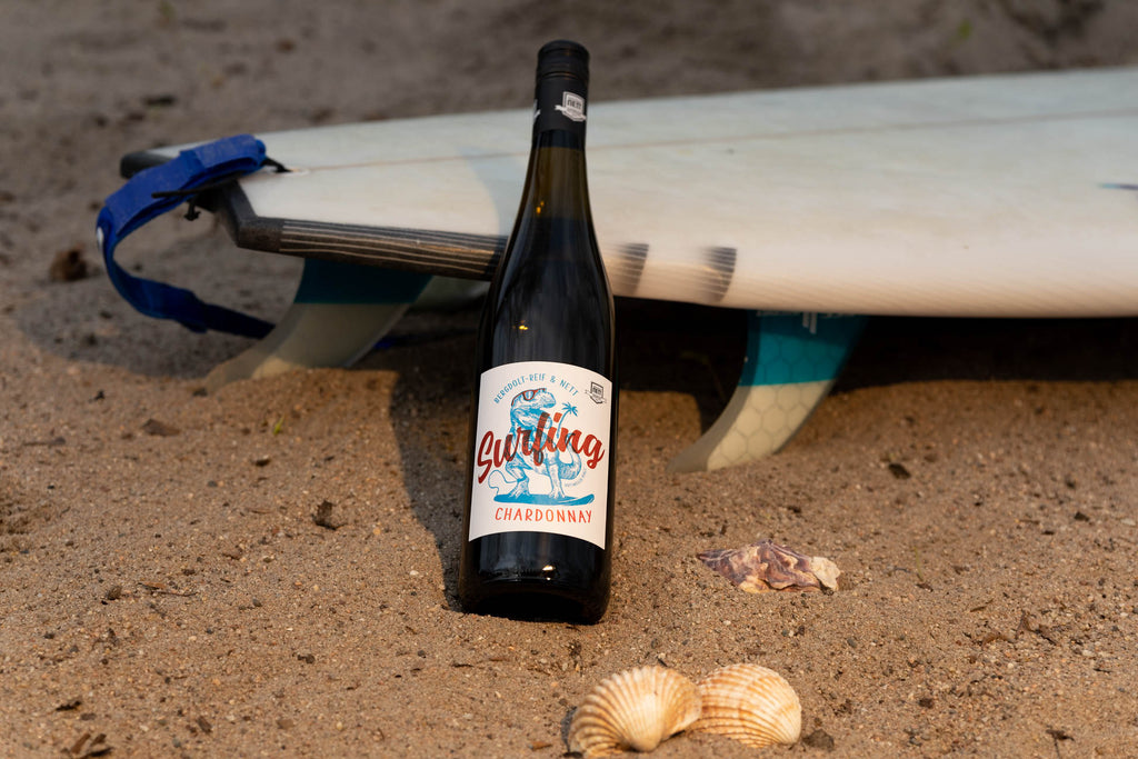 Surfing Chardonnay Dino von Bergdolt-Reif und Nett aus der Pfalz - Weinflasche an Surfbrett im Sand