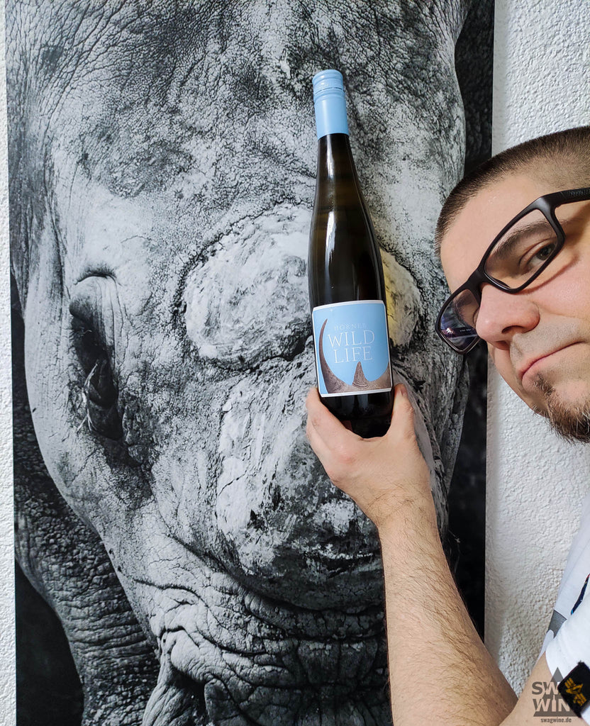 Wildlife Weißwein Cuvee von Weingut Hörner, Pfalz - Weinflasche vor Foto von Nashorn gehalten mit Markus Ulrich von Swagwine